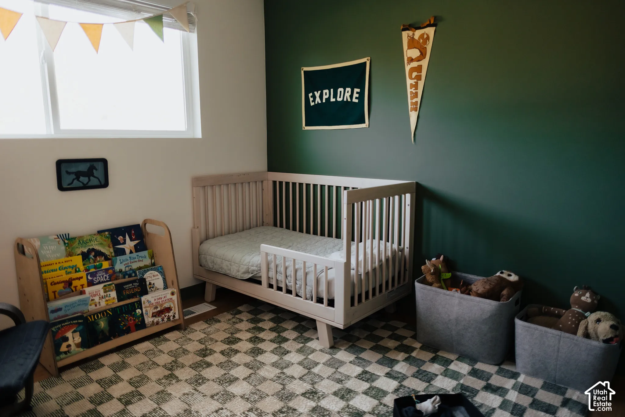 Room featuring a deep green accent wall, large rectangular window, and neutral-tone wall-to-wall carpeting