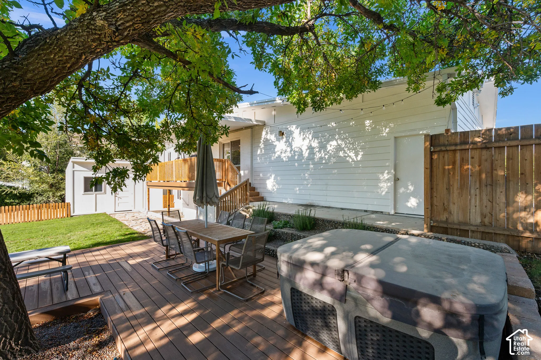 Expansive wood-finish deck, multi-level outdoor living space, privacy fencing, and a separate structure with a white exterior