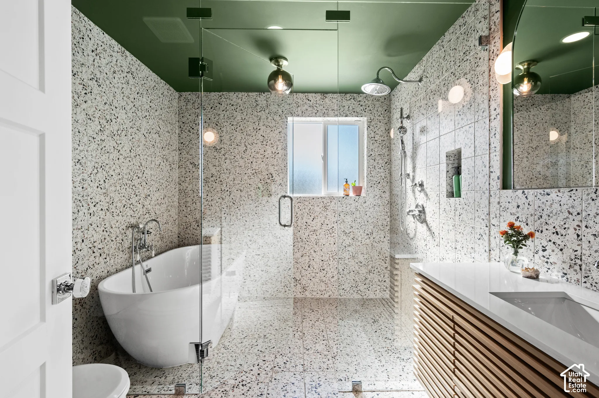Bathroom featuring a freestanding soaking tub, glass-enclosed shower, wood-slat vanity with integrated sink, and an accent ceiling