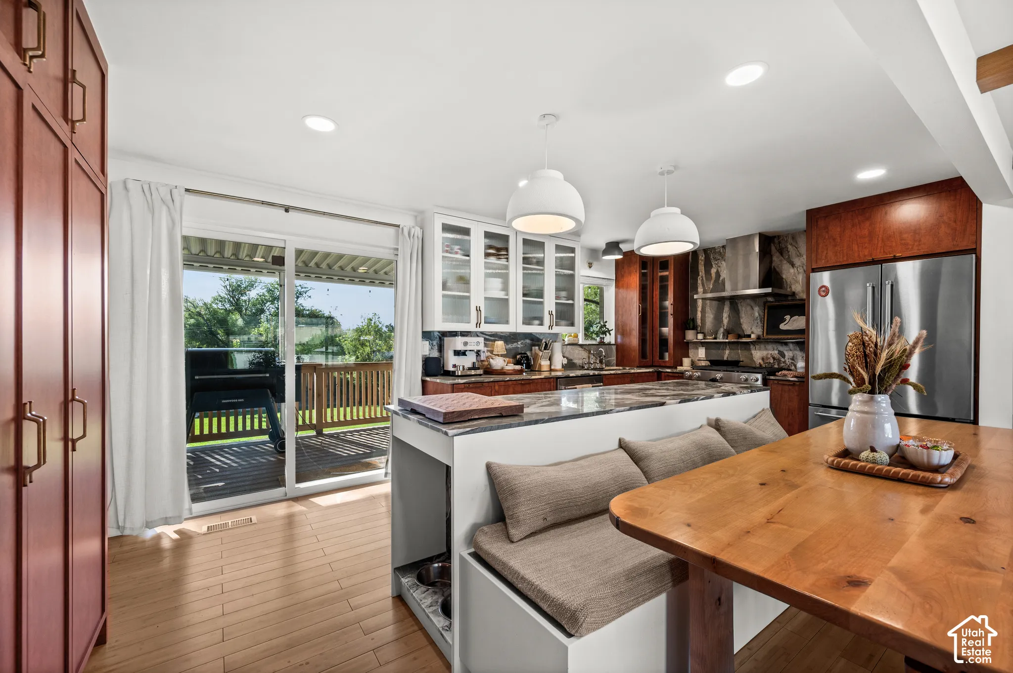 Open-concept kitchen with wood-finish flooring, built-in banquette seating, and a large central island