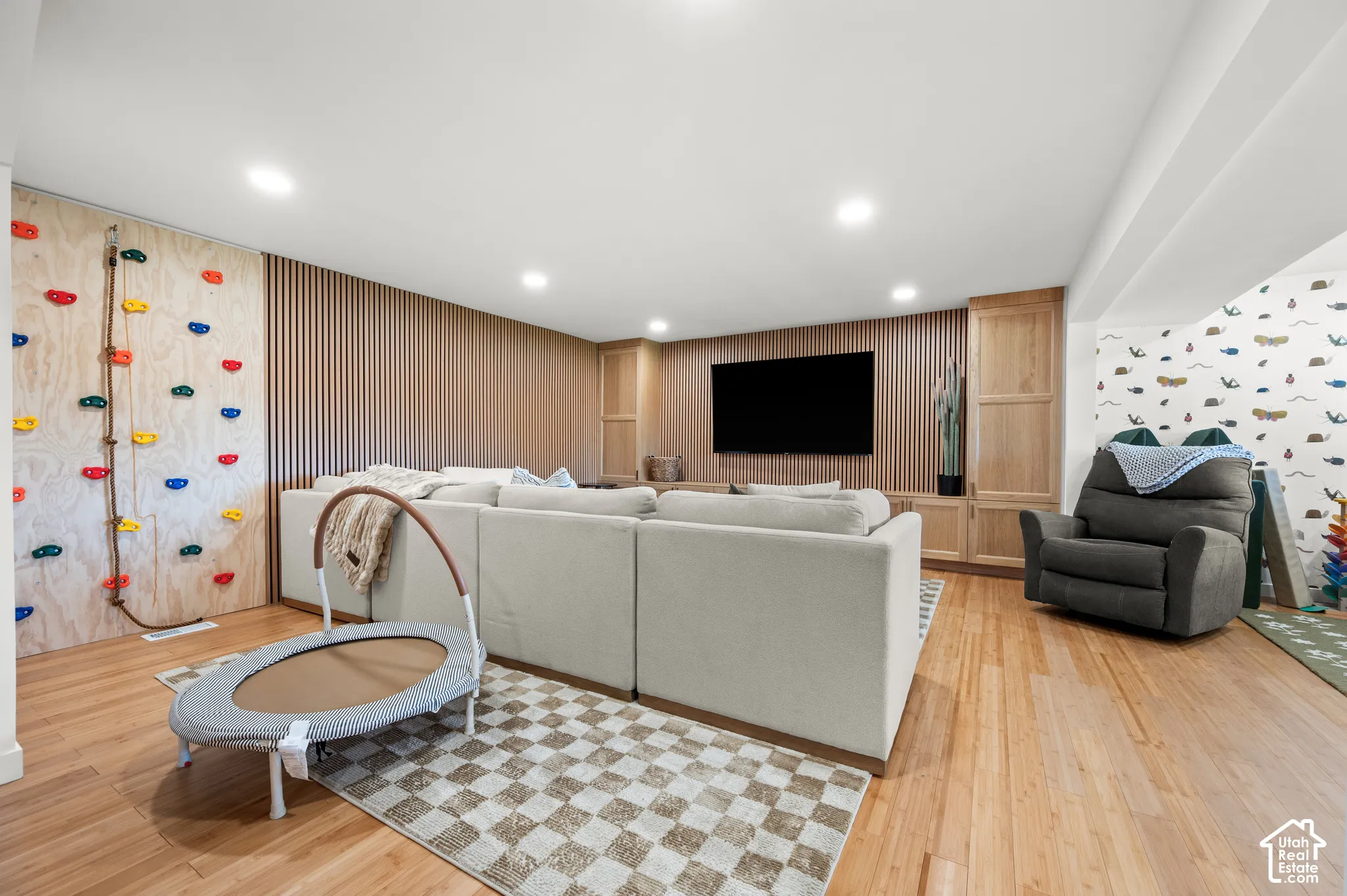 Wood-finish flooring, recessed lighting, accent wall with vertical wood paneling, and built-in cabinetry with integrated display space