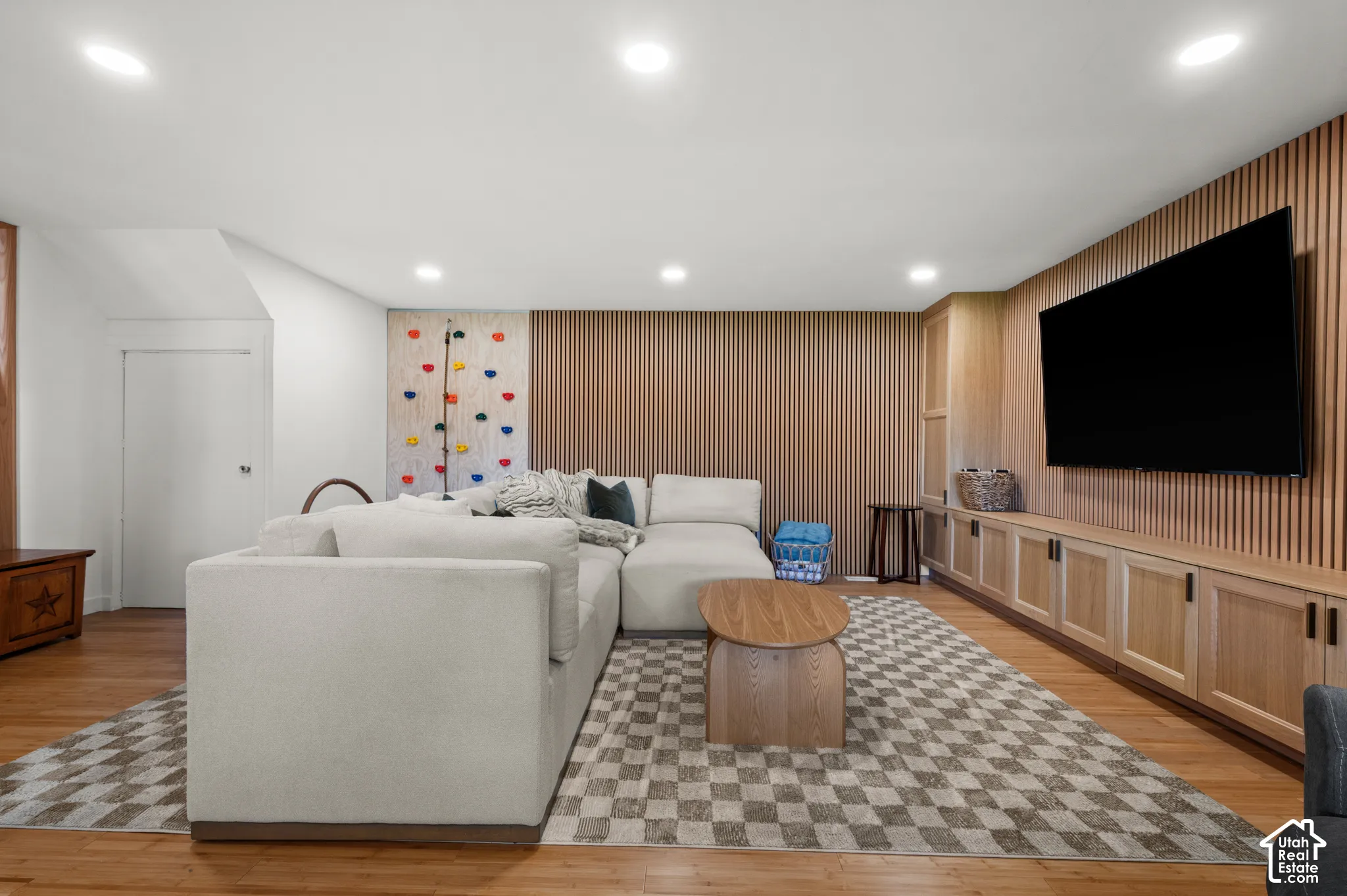 Hardwood-finish flooring throughout, recessed ceiling lighting, a built-in entertainment center with wood cabinetry, and a textured accent wall