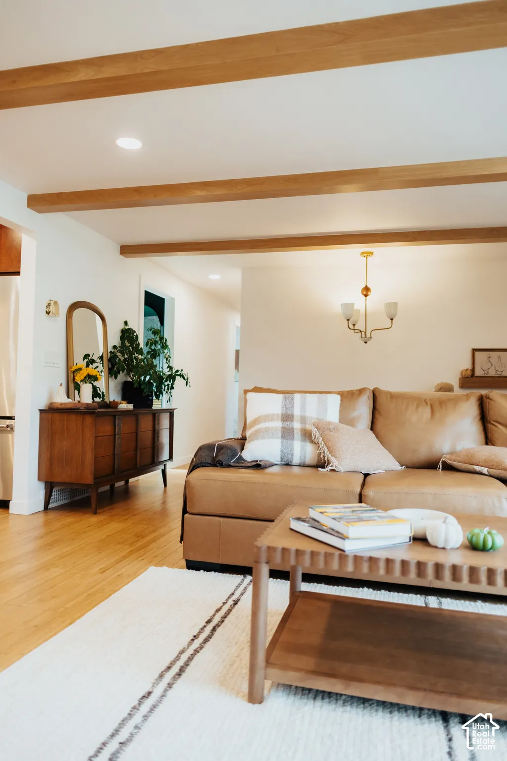 Exposed natural wood ceiling beams, recessed lighting, and wood-finish flooring complemented by a multi-arm metallic chandelier