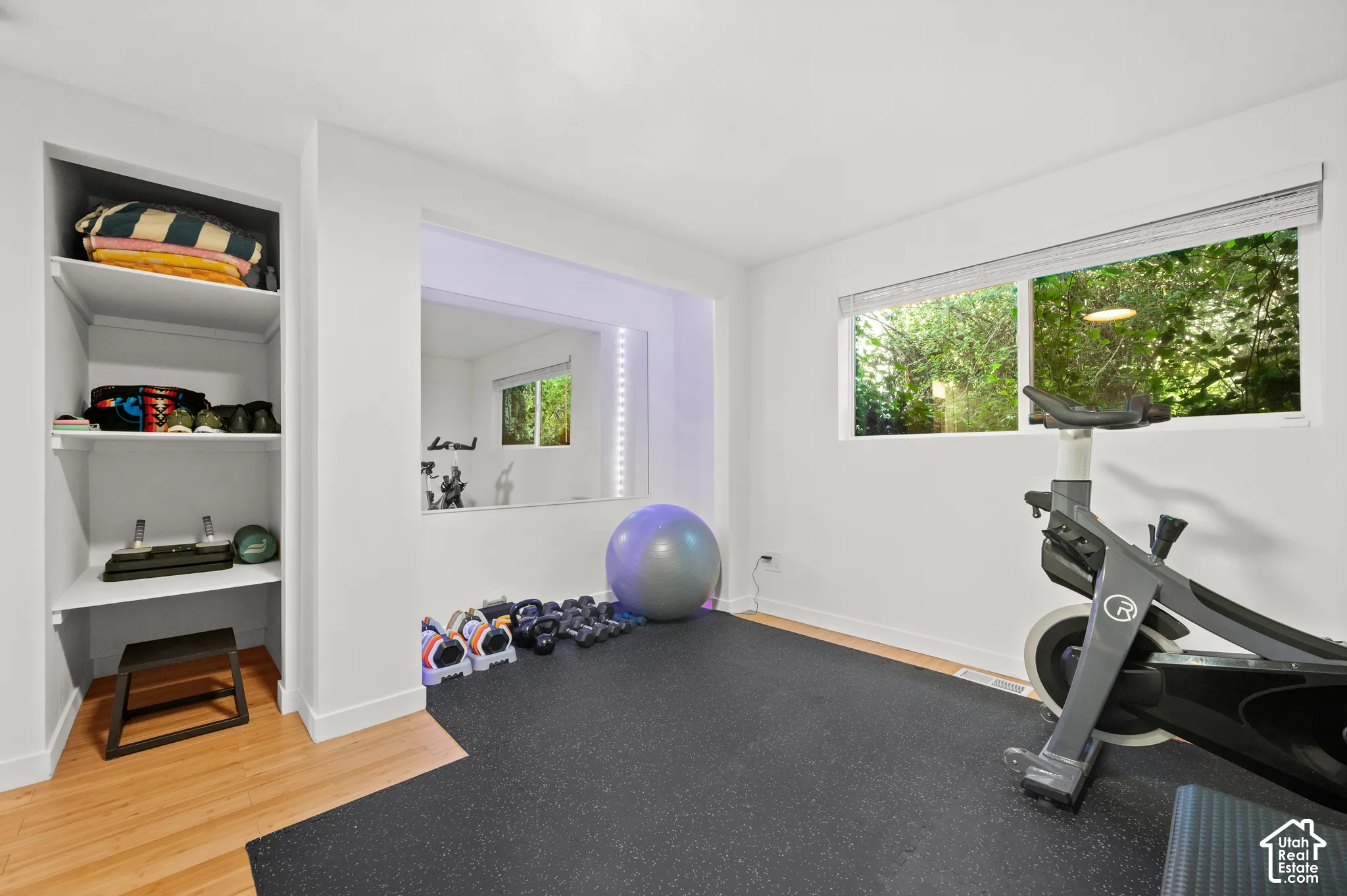 Built-in shelving, recessed mirror with integrated lighting, rubber flooring, and wood-finish flooring