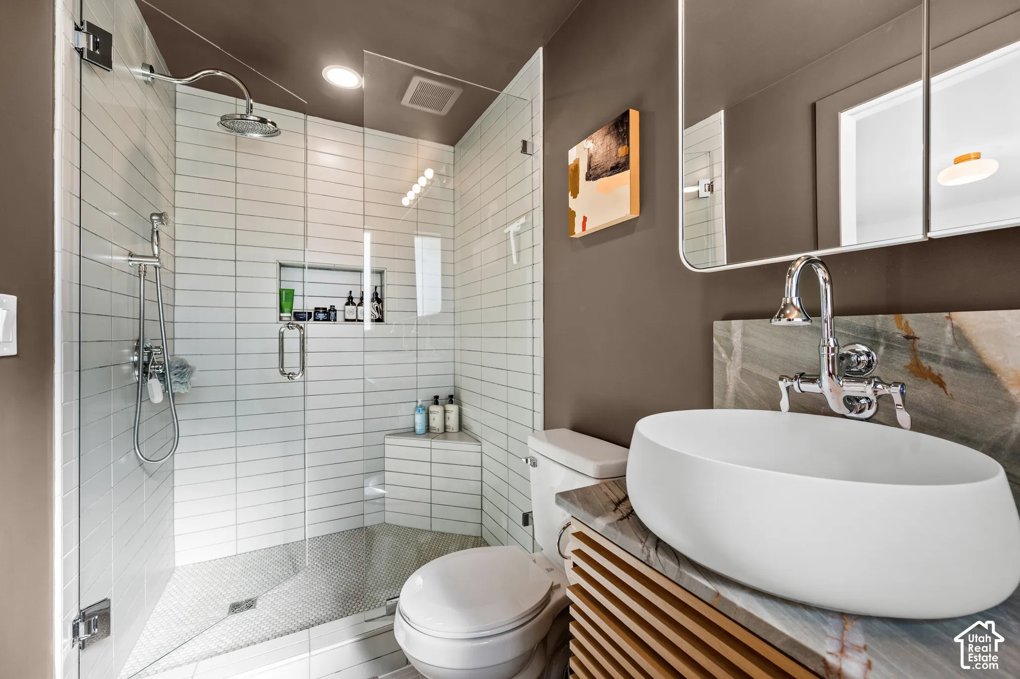 Glass-enclosed shower with white subway tile, built-in shower niche, and corner bench