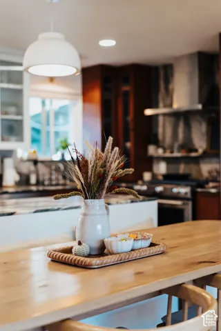 Kitchen featuring custom dark-toned cabinetry, high-contrast countertop with a prominent island, professional-grade range with a stainless steel vent hood, and a pendant light fixture