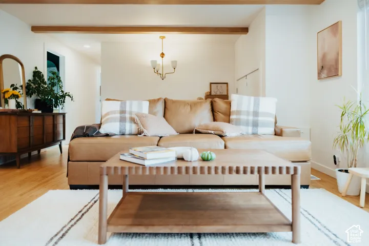 Exposed wood ceiling beams, wood-finish flooring, and a multi-arm brass chandelier