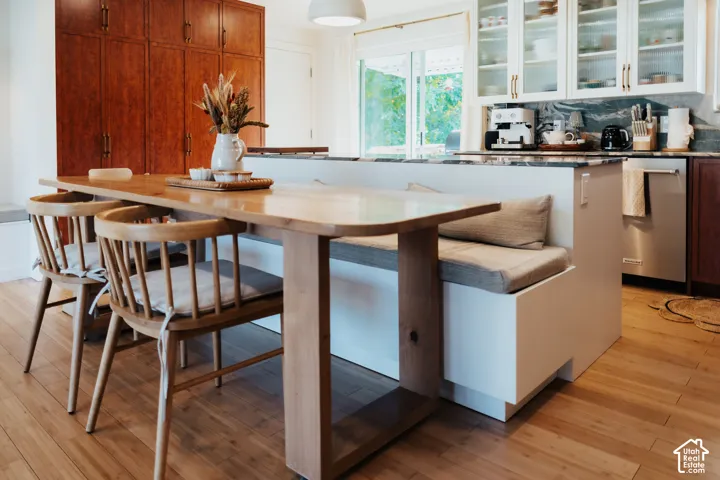 Kitchen featuring wood-finish flooring, floor-to-ceiling wooden cabinetry, stone-surface countertops, glass-front upper cabinets, and a built-in banquette