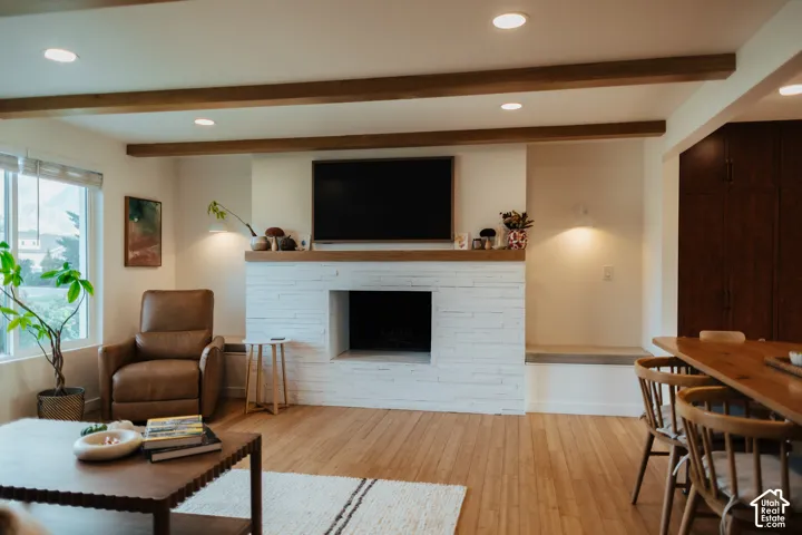 White painted brick fireplace featuring a wood mantel, wood-finish flooring, exposed ceiling beams, recessed lighting, and built-in alcove benches