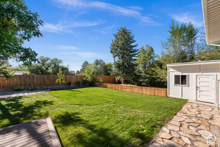 Expansive lawn area, composite decking, flagstone patio, privacy fencing, and a detached structure with a window and solid panel doors