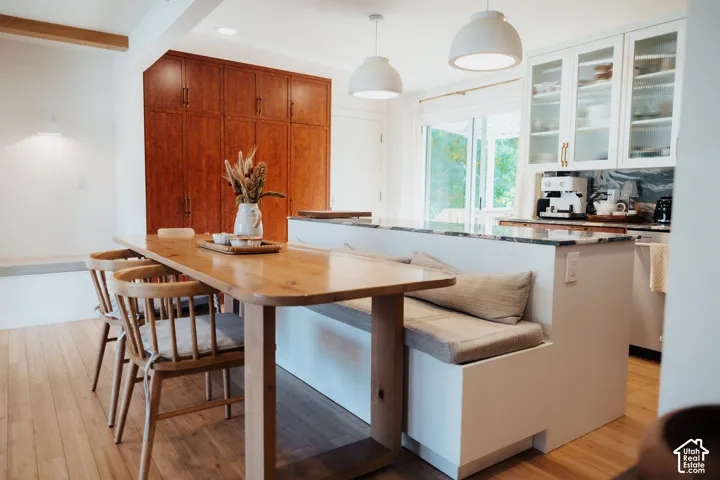 Kitchen featuring wood-finish flooring, floor-to-ceiling wood cabinetry, a central island with a built-in bench, stone countertops, and glass-front upper cabinets