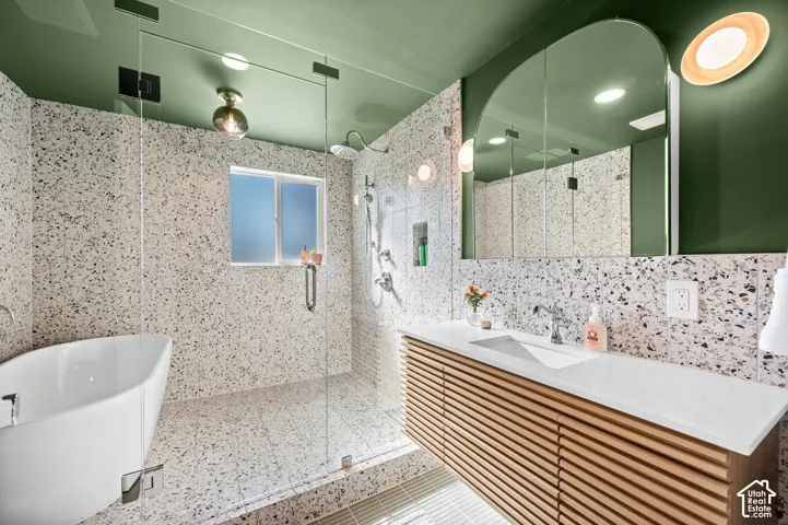 Freestanding soaking tub, walk-in shower with glass enclosure, floating vanity with slatted wood-finish cabinetry, integrated sink, and an arched mirror