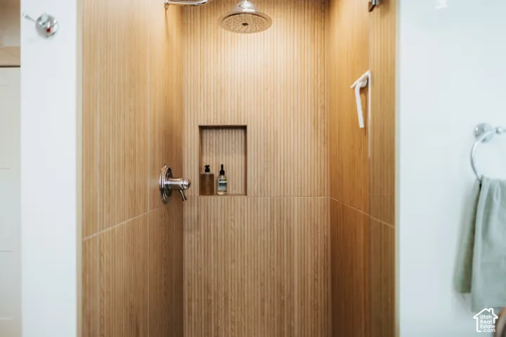Shower featuring vertically-ribbed, wood-finish wall panels, a polished chrome rainfall shower head, single-handle pressure balance valve, and a built-in recessed niche