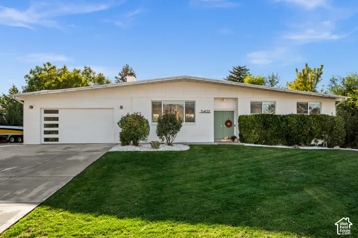 Ranch-style exterior with a low-slope roof, light green front door, and a modern garage door with frosted glass panels