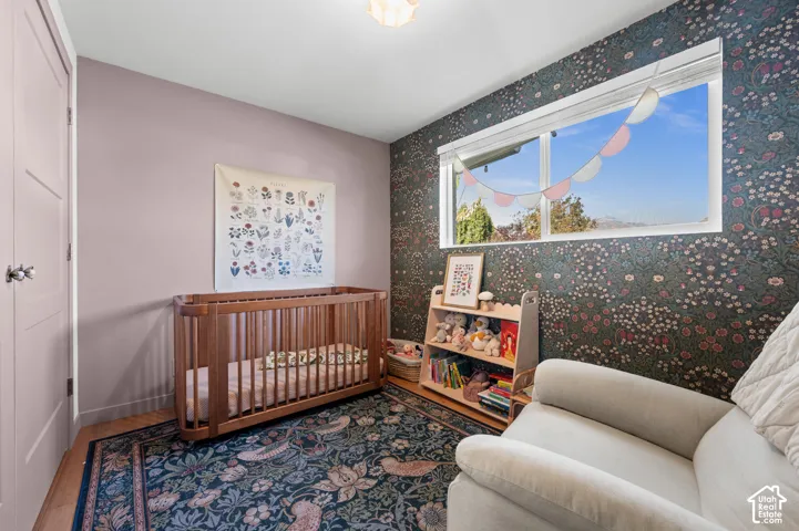 Picture window with white trim, patterned wallpaper, light wood-finish flooring, and a flush-mount ceiling light fixture