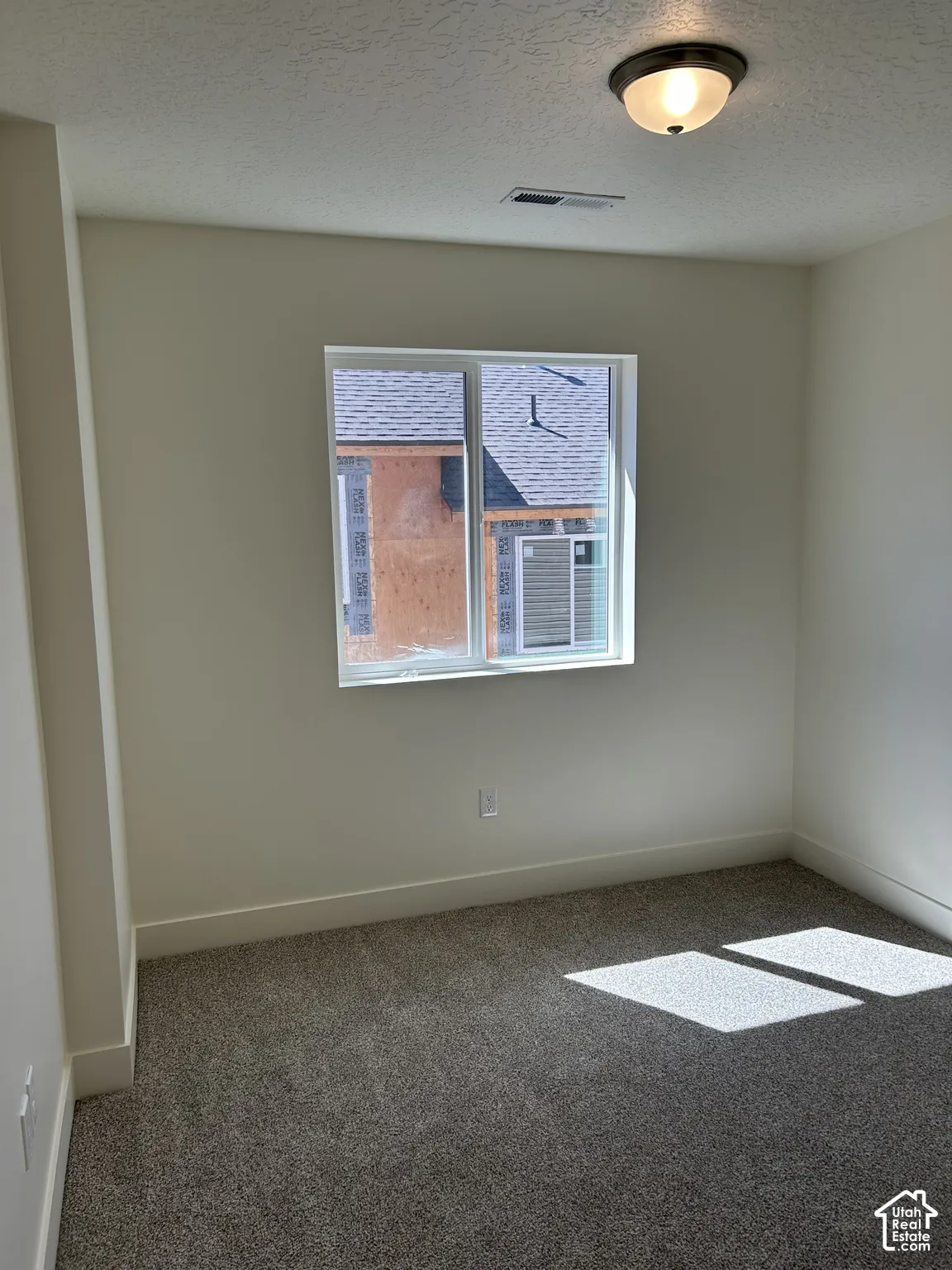 Recessed window with white trim, neutral-toned walls, and grey textured carpeting