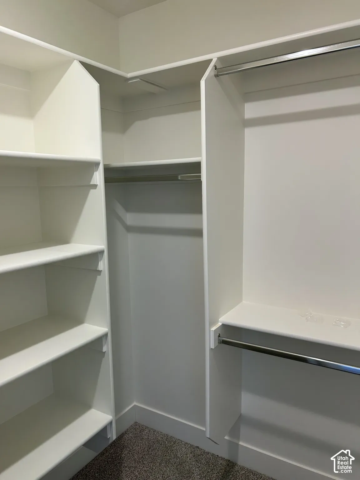 Built-in custom shelving, multiple hanging rods, and dark gray carpeting