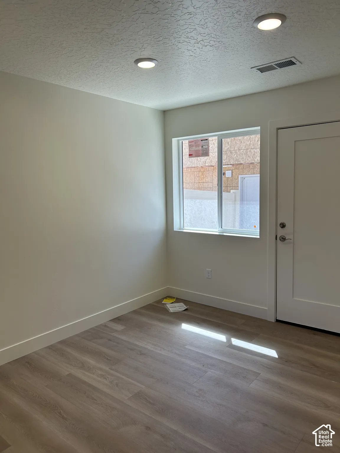 Recessed ceiling lighting, wood-finish flooring, and a white interior door with contemporary hardware