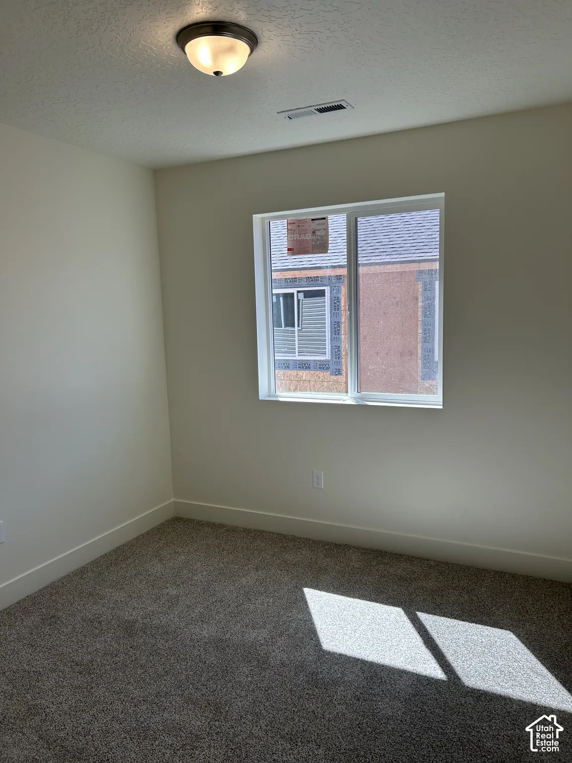 Neutral-toned wall finish, gray-toned carpeting, and a single window with a white frame