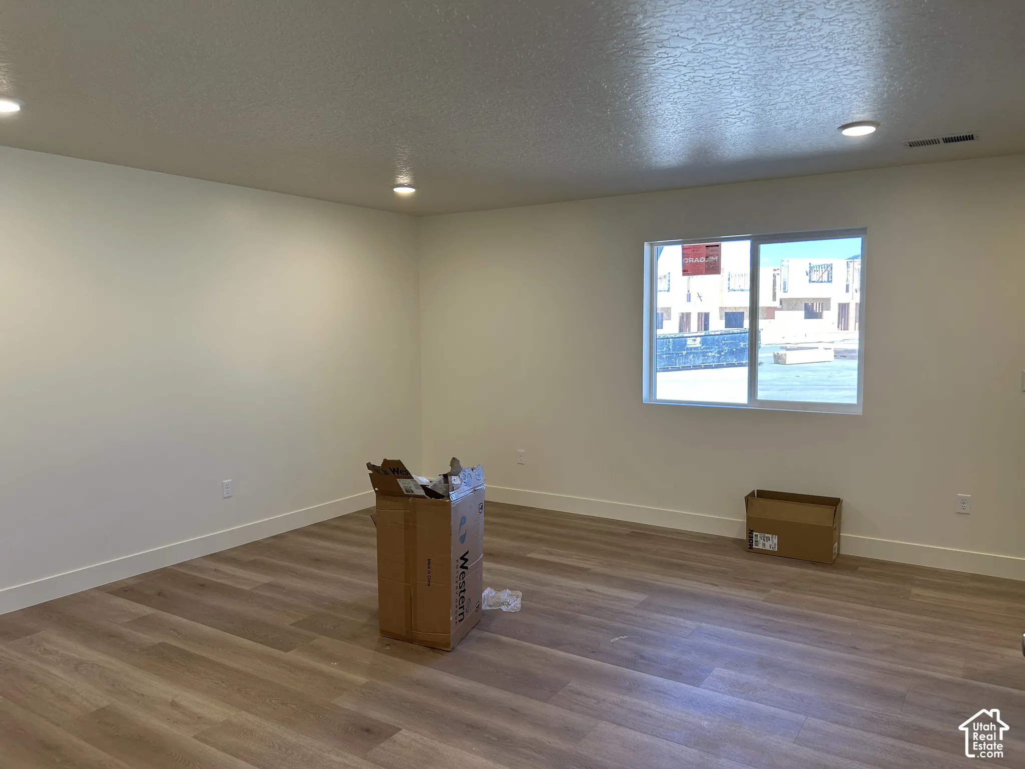 Recessed lighting, light-toned walls, wood-finish flooring, a white-framed window, and white trim