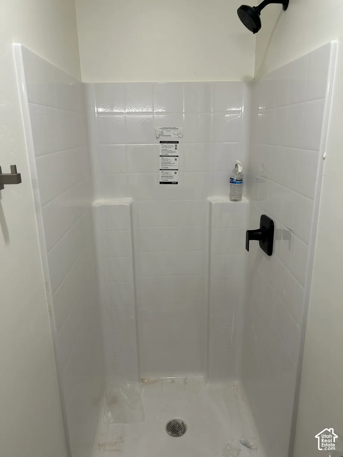 White tiled shower with a matte black showerhead and single-handle faucet