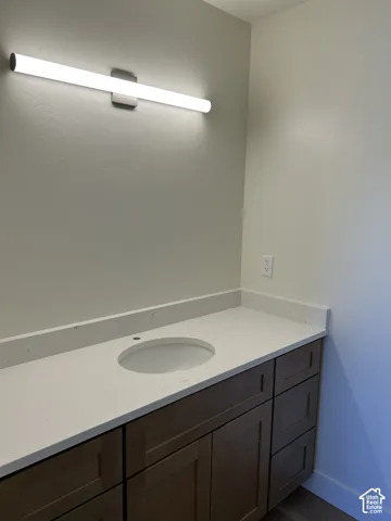 Vanity with a white countertop, undermount sink, and wood-finish cabinetry