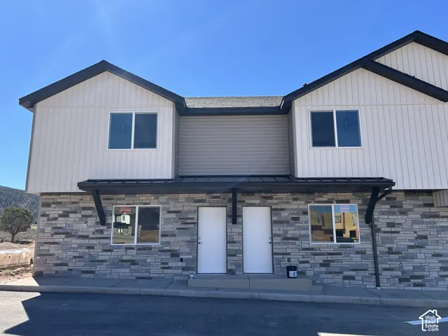 Two-story exterior with a combination of light-colored vertical siding and horizontal gray siding, accented by dark rooflines