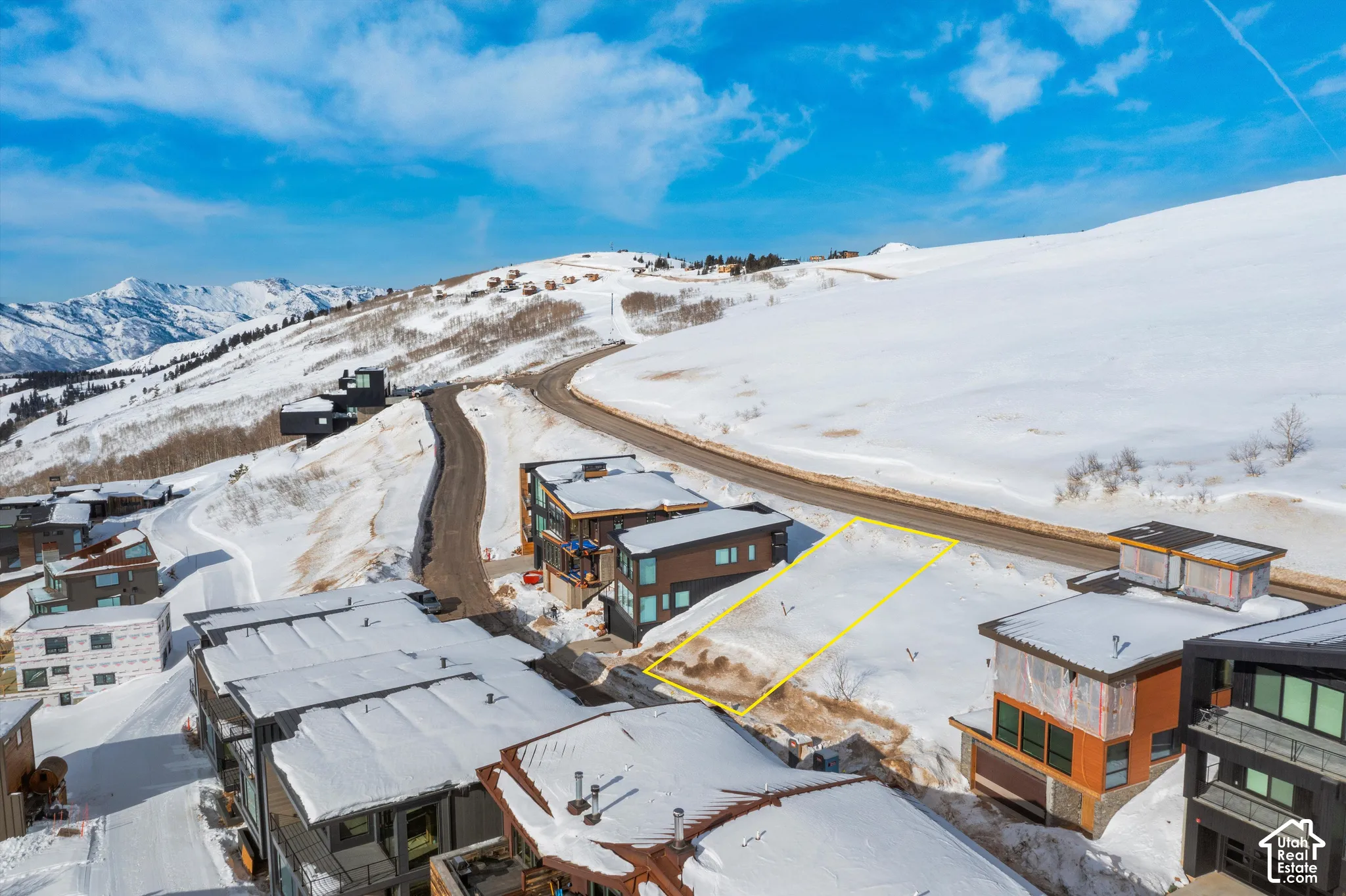 Snow-covered mountain setting with a paved road and surrounding structures