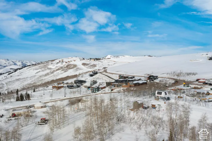 Snow-covered mountain landscape featuring multiple properties, winding roads, and a ski lift infrastructure