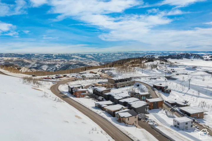 Mountainous terrain with a paved road, multiple residential structures, and a clear sky