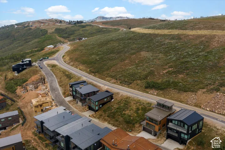 Mountainous terrain with established roads, modern architectural homes, and ongoing construction