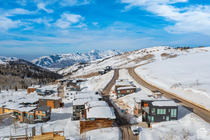 Snow-covered mountainous terrain featuring a paved road and surrounding residential structures