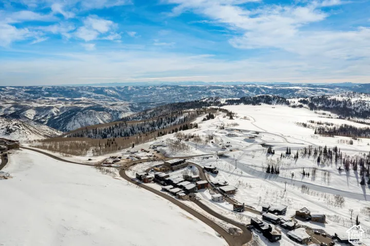 Mountainous terrain with expansive snow-covered landscapes, numerous properties, and paved access roads