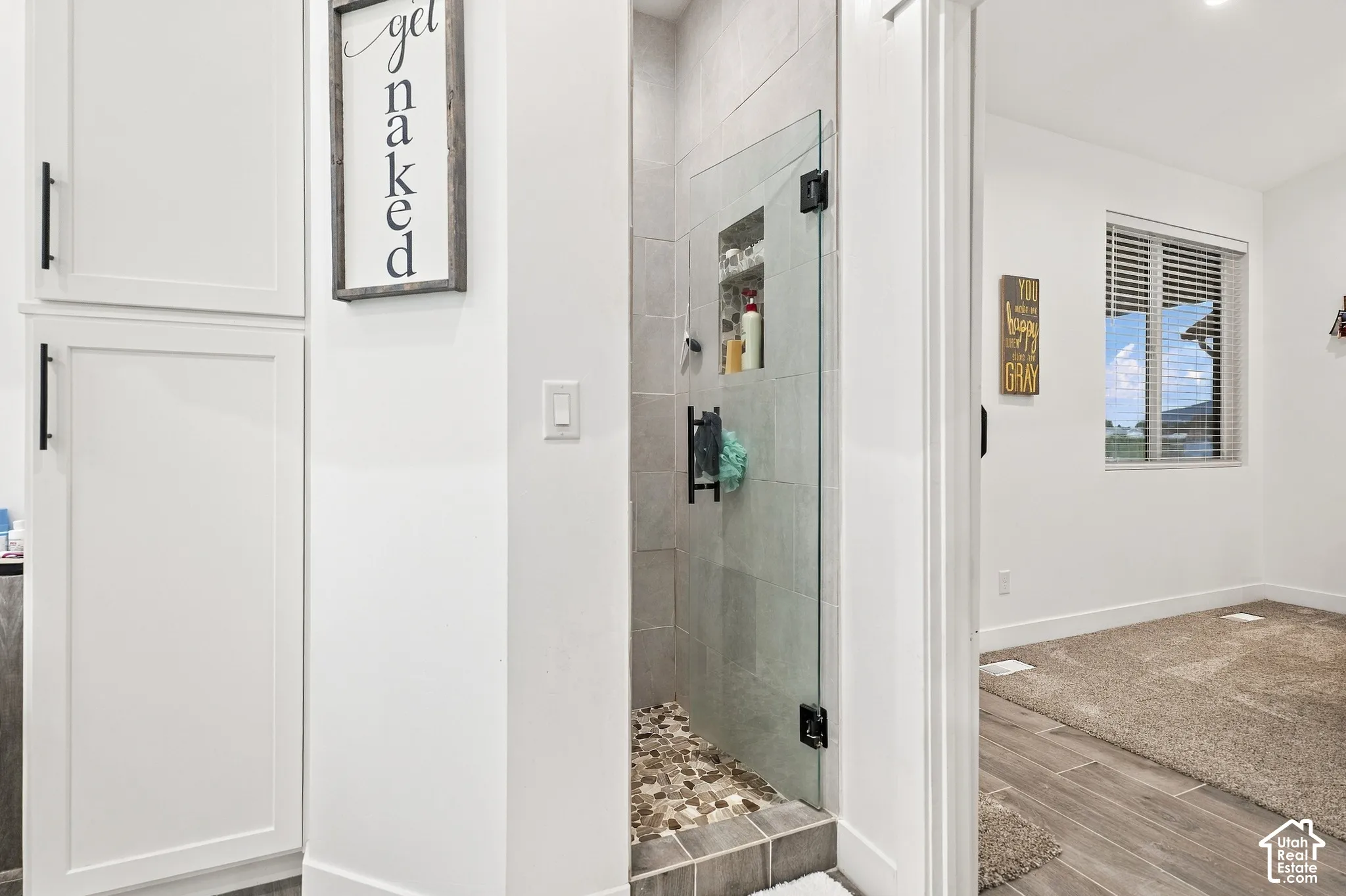 Glass-enclosed shower with tiled walls and river rock flooring