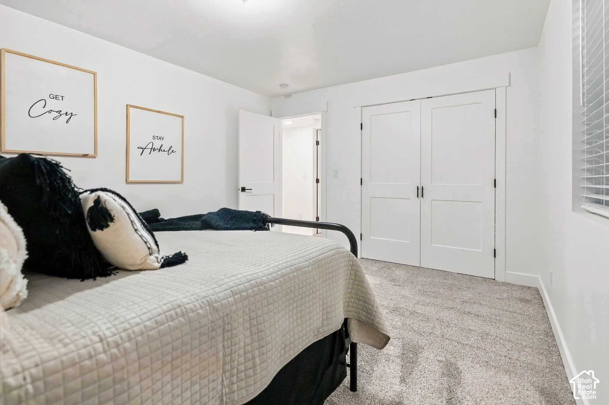 Soft textured carpeting, white painted walls, and a window with horizontal blinds