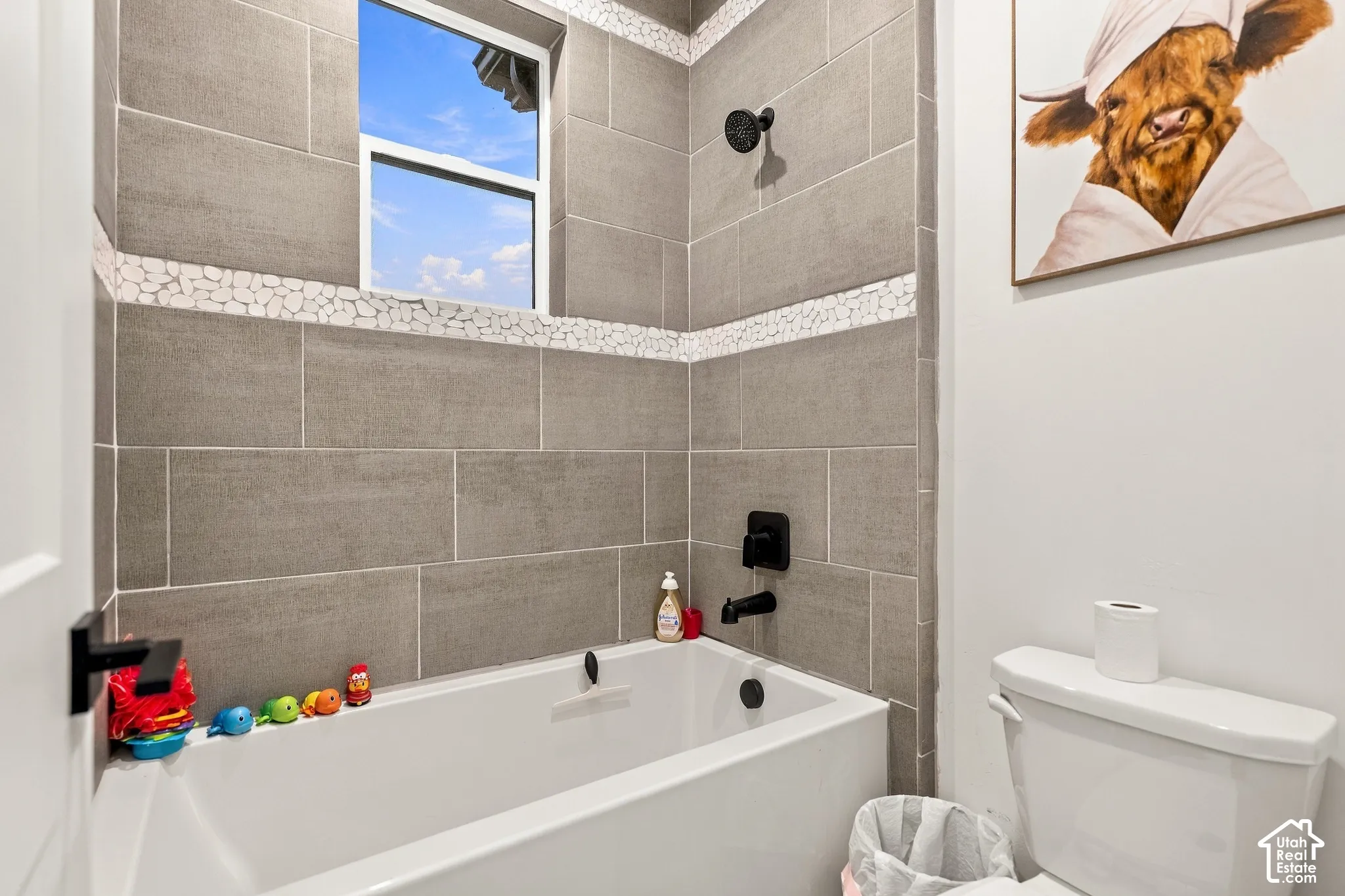 Tiled shower and bath combination with a white tub and matte black fixtures