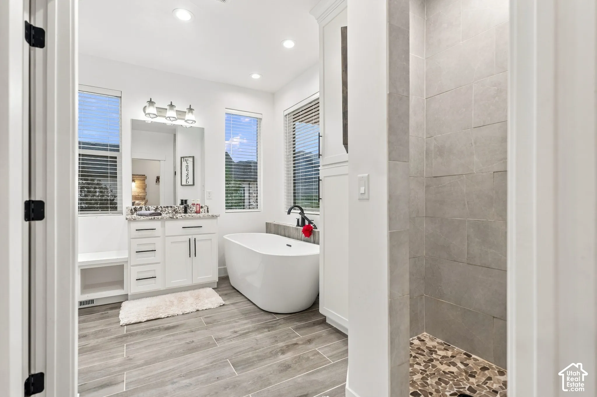 White vanity with granite-style countertop, undermount sink, and three-light fixture
