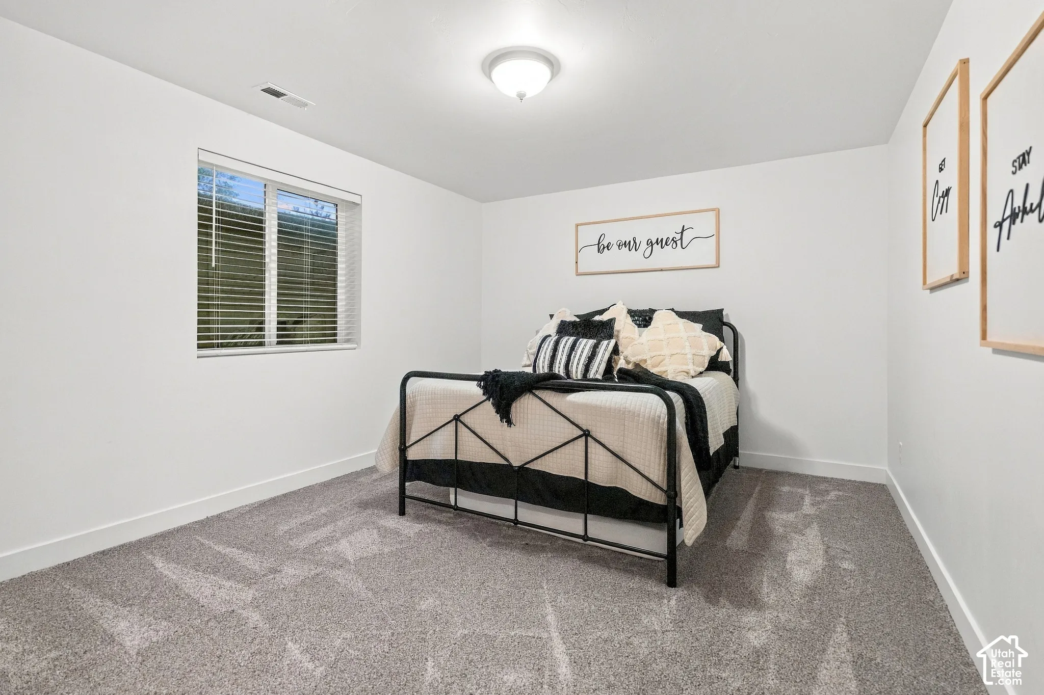 White walls with gray carpet, a single window, and a ceiling-mounted light fixture