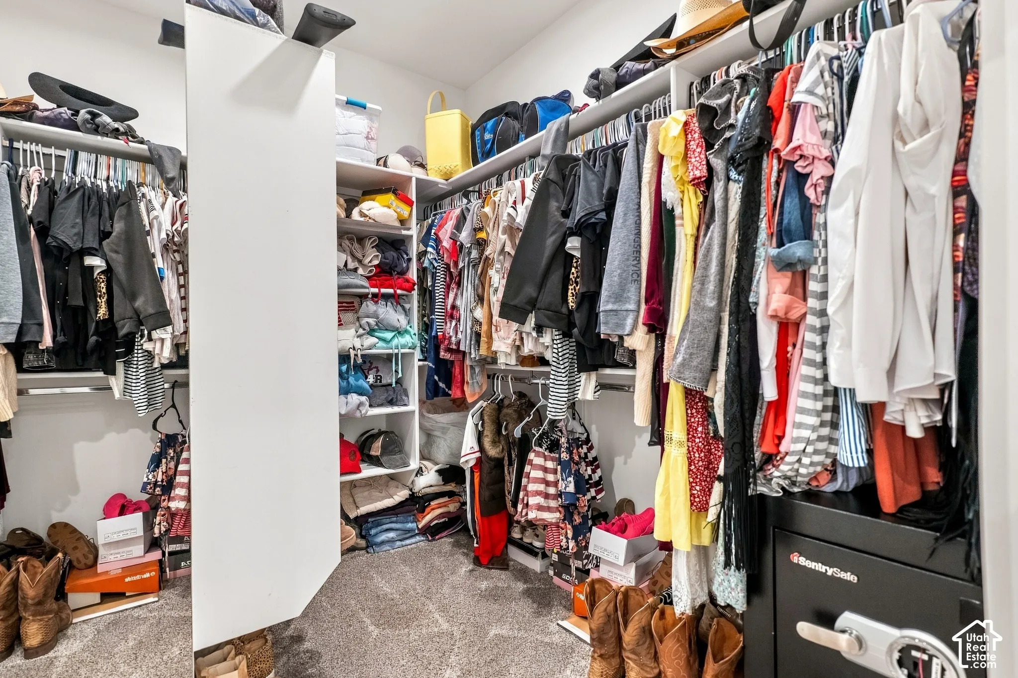 Built-in shelving and hanging rods in a walk-in closet with carpet flooring