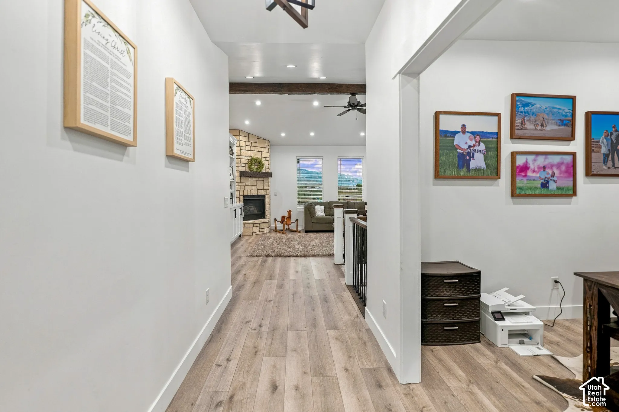 Wood-finish flooring throughout, natural stone fireplace surround, exposed wood beam ceiling accent, recessed lighting, and expansive windows
