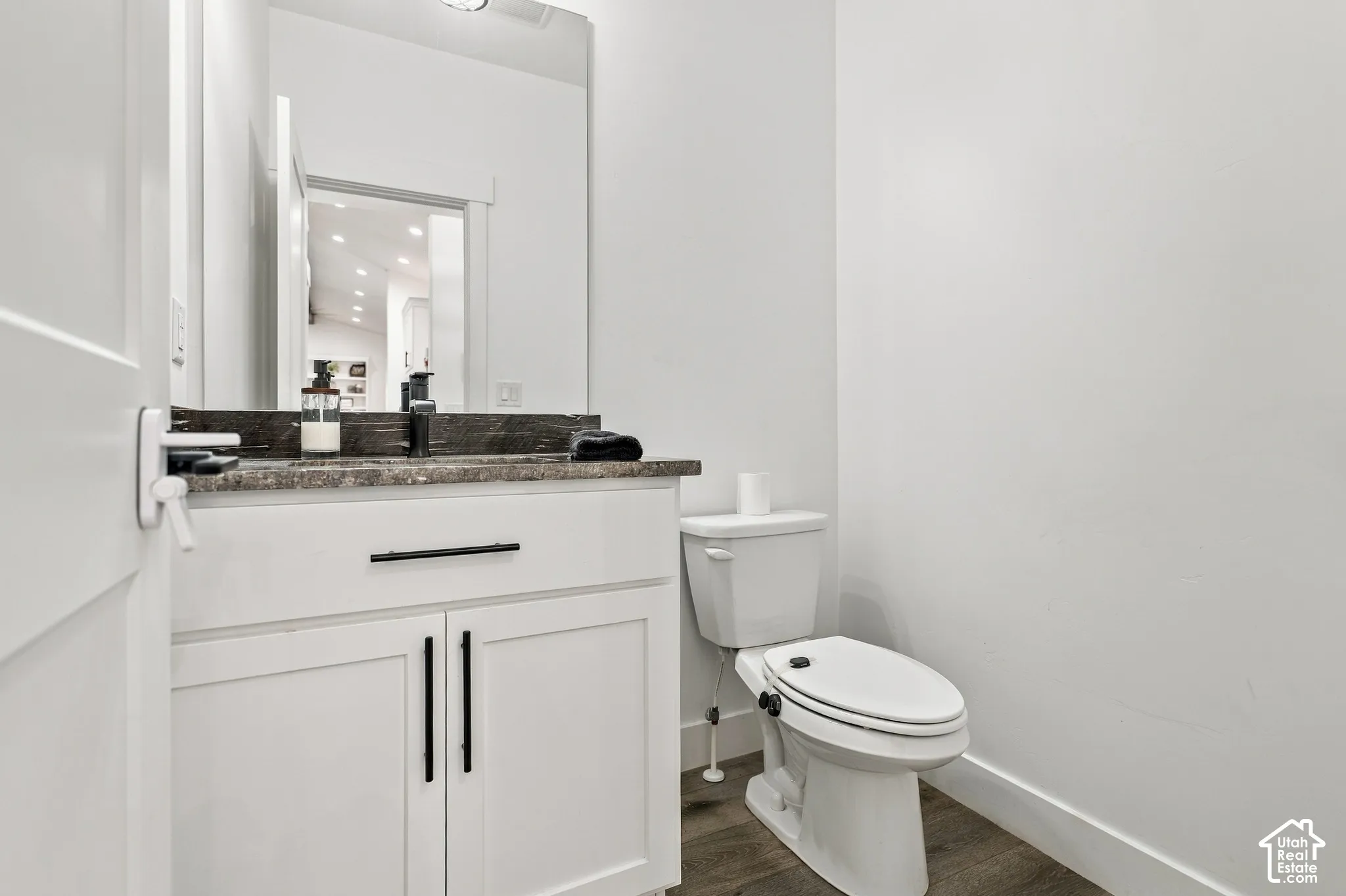 White vanity with dark stone-finish countertop, undermount sink, and black fixtures