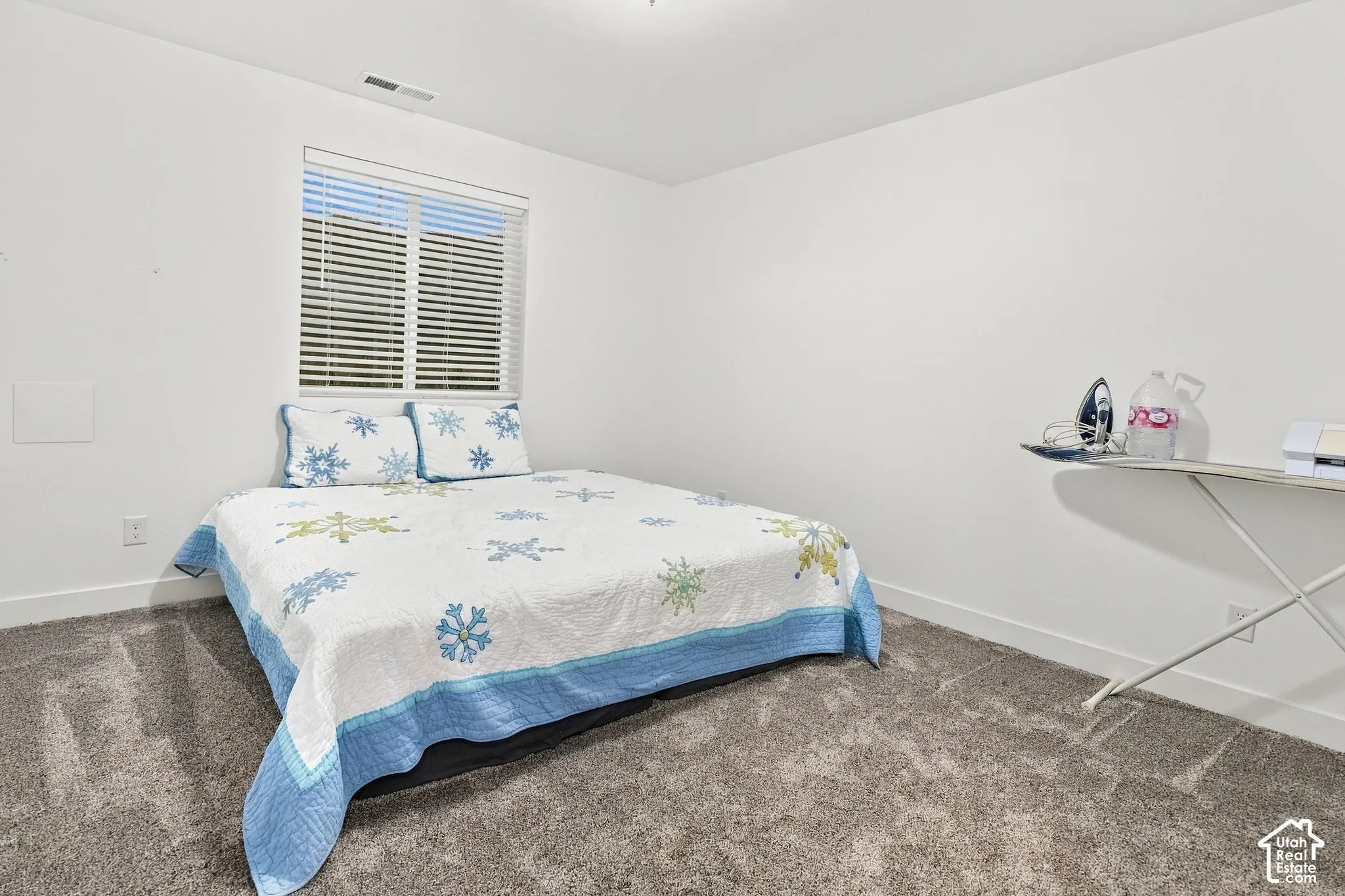 Carpeted flooring, white walls, and a window with horizontal blinds