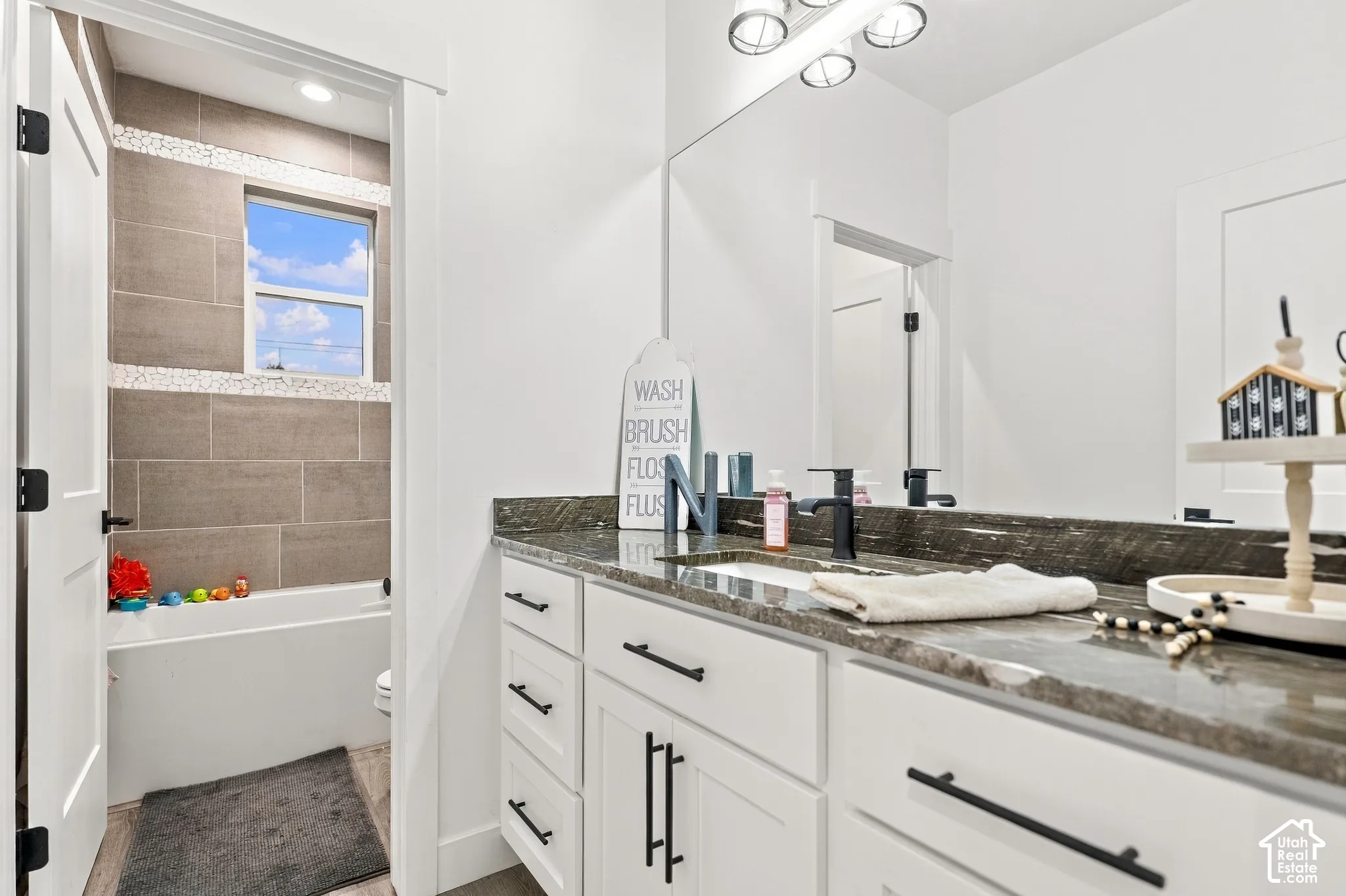 Bathroom vanity featuring a dark stone countertop, undermount sink, and black wall-mounted faucet