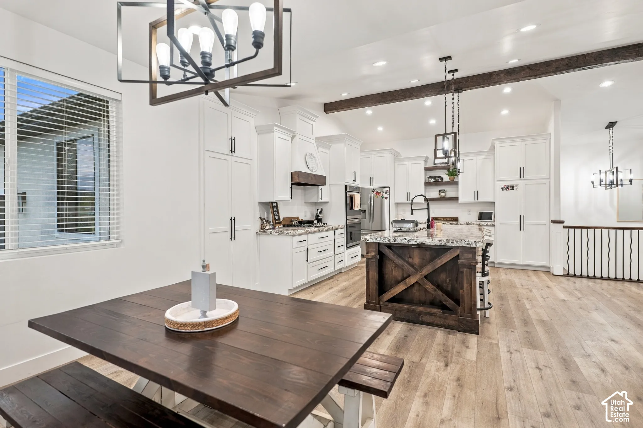 Open-concept kitchen with white cabinetry, granite countertops, wood-finish flooring, and a dark wood island