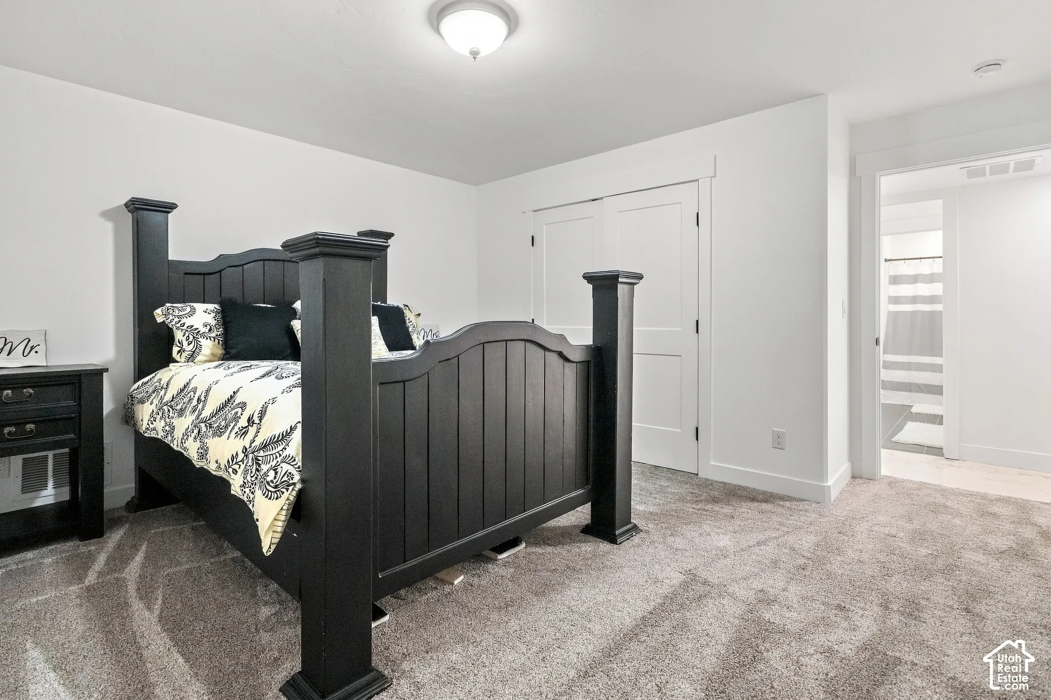 Recessed ceiling light, white walls, gray carpet, and white bi-fold closet doors