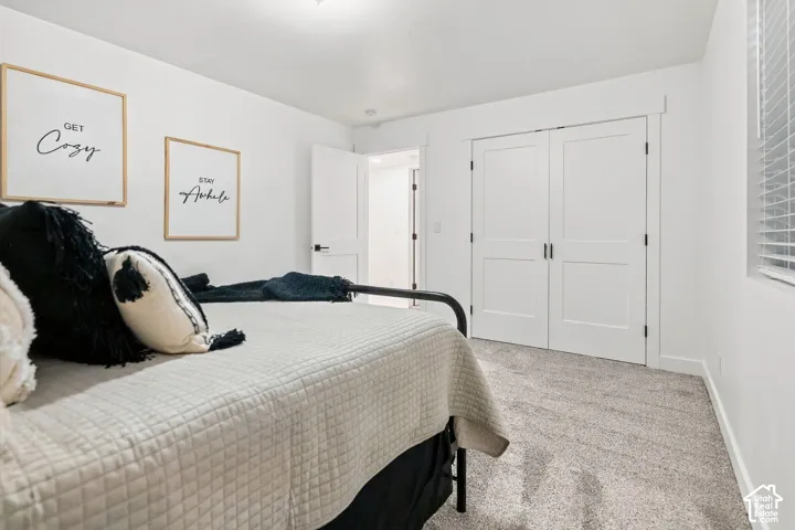Soft textured carpeting, white painted walls, and a window with horizontal blinds