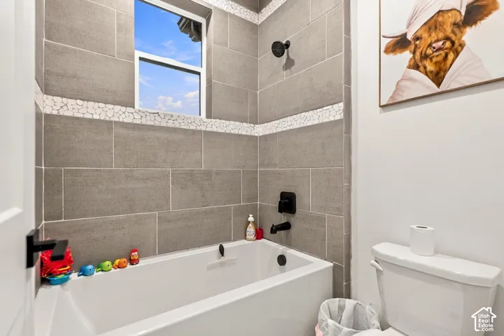 Tiled shower and bath combination with a white tub and matte black fixtures