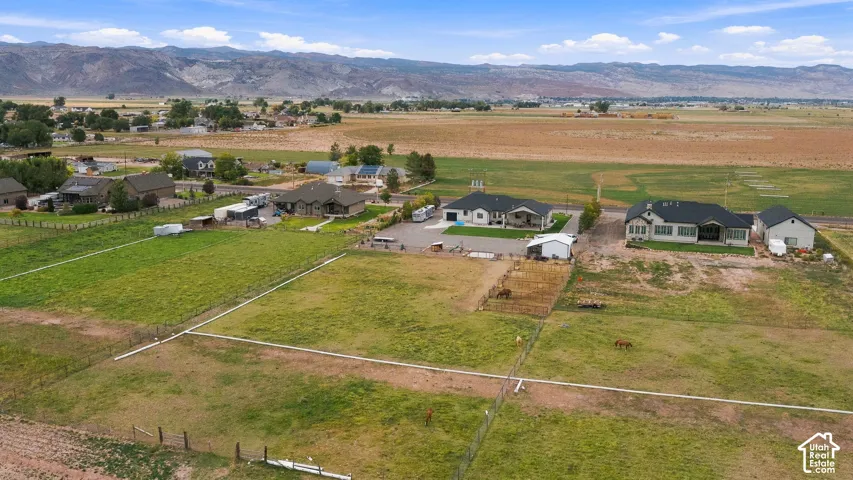 Expansive property with multiple structures, large fenced green spaces, and mountain terrain in the background