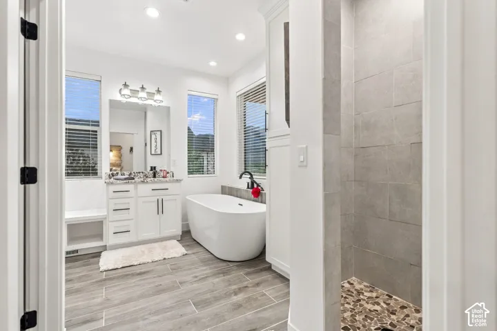 White vanity with granite-style countertop, undermount sink, and three-light fixture