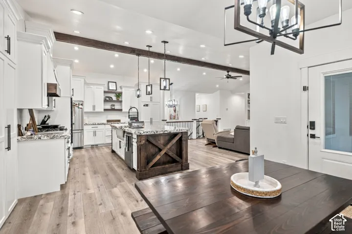 Kitchen featuring white cabinetry, wood-finish flooring, a wood-finish island with stone countertops, and stainless steel appliances